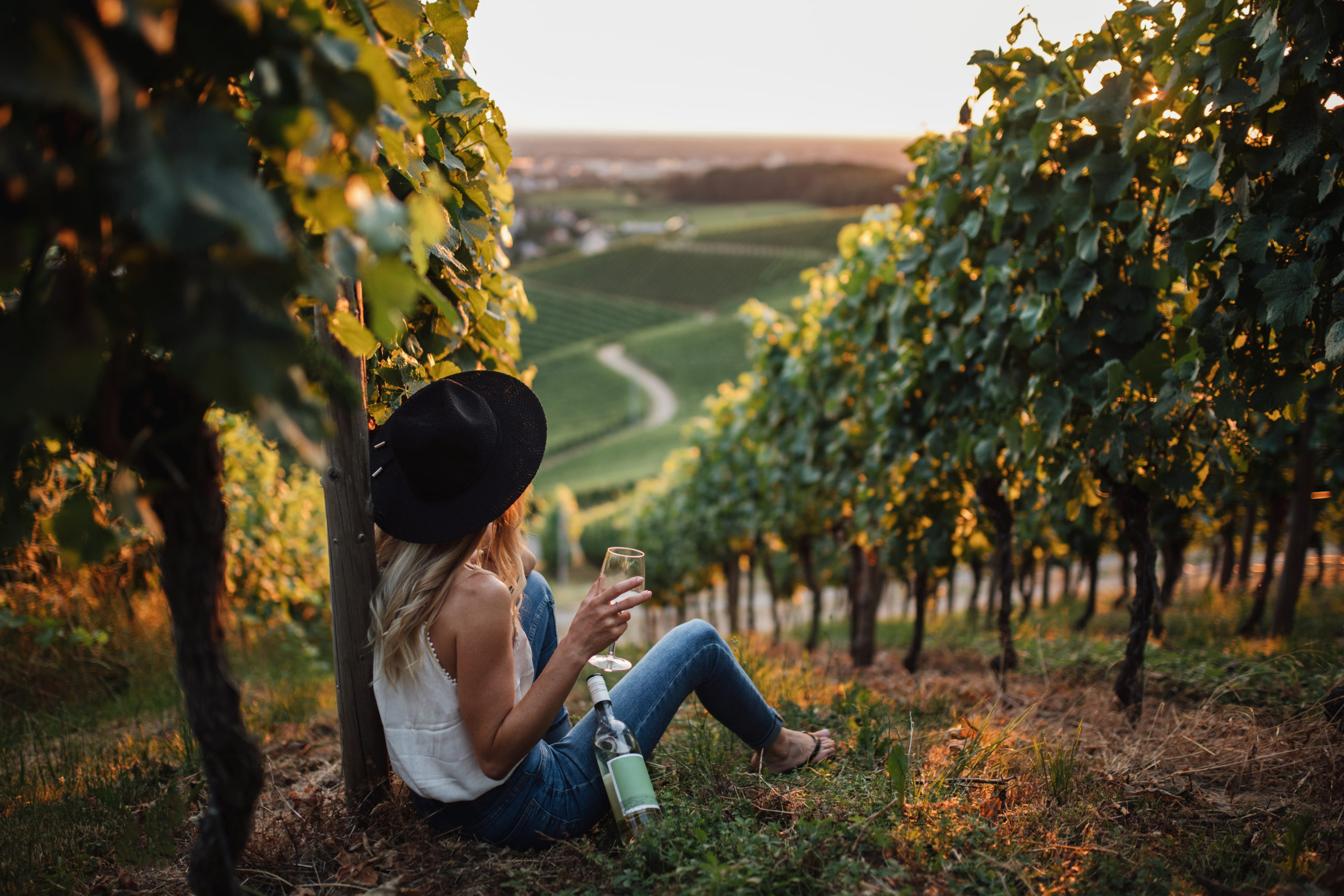 young-blonde-woman-relaxing-vineyards-summer-season-with-bottle-wine